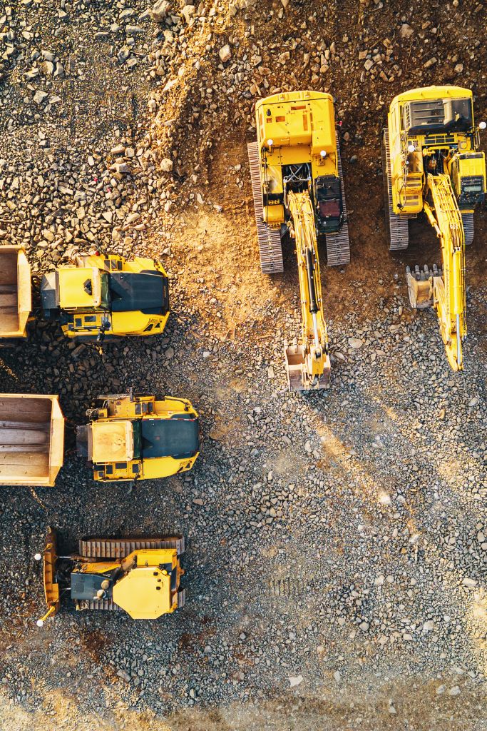 Aerial drone view of five forklifts operating within a bustling construction site, showcasing organized site management.