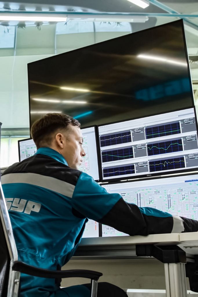 An IT technician in a control room monitoring critical functionalities at an oil and gas facility, ensuring operational continuity.