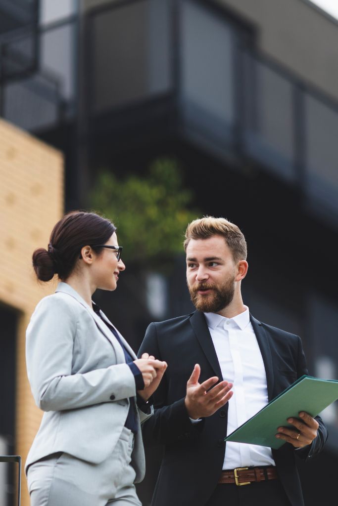 Two real estate agents engaged in a discussion, possibly over digital tools and IT solutions for real estate.