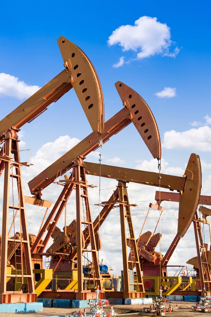 Multiple oil cranes operating in an expansive oil field, demonstrating the scale of industry operations.