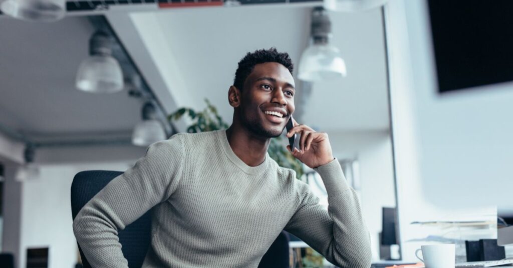 Man engaged in a conversation using a VOIP phone in an office setting.