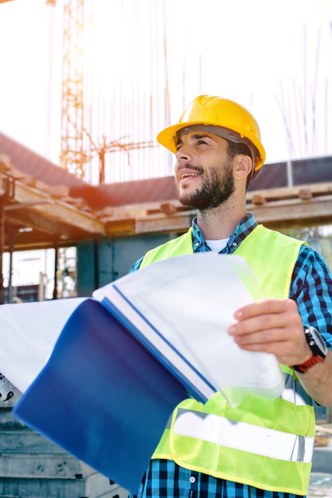 A supervisor holding a blue folder and directing work at a construction site, highlighting effective project management supported by IT services.