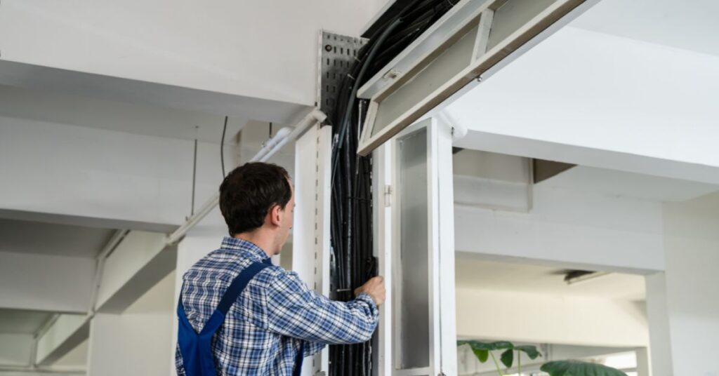 A technician carefully running cables along the inside of a structural column in an office setting, demonstrating professional cable installation.