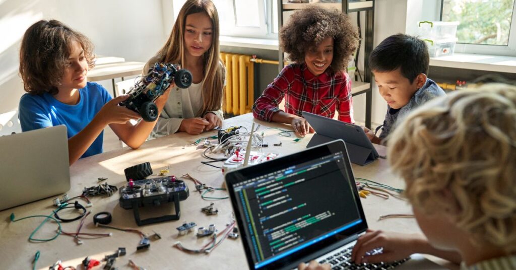 Group of diverse students collaborating on a robotics project with laptops, supported by IT GOAT's expert IT services to enhance technological learning in schools.