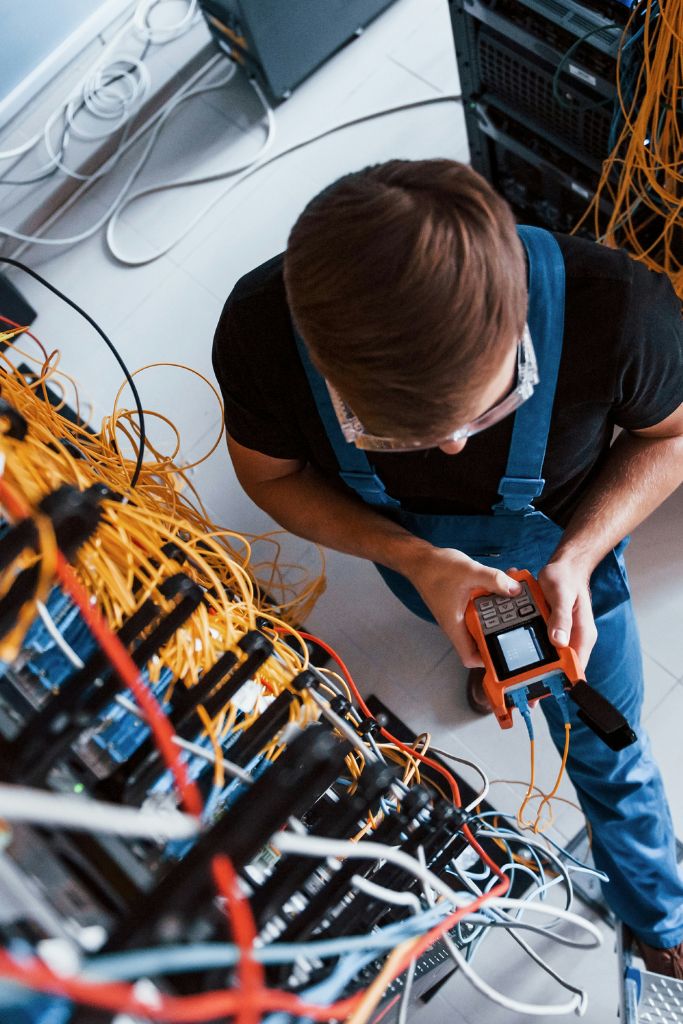 Technician working on network cables, representing hands-on managed IT services offered by IT GOAT in Austin, TX.
