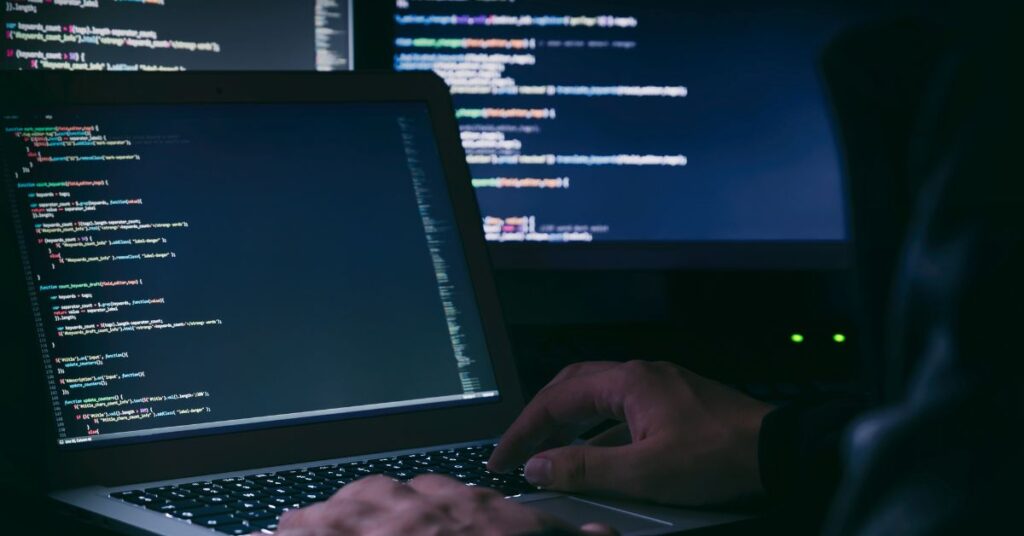 A cybersecurity professional coding on a laptop, illustrating IT GOAT's advanced solutions designed to protect nonprofit organizations from cybercriminals and data breaches.